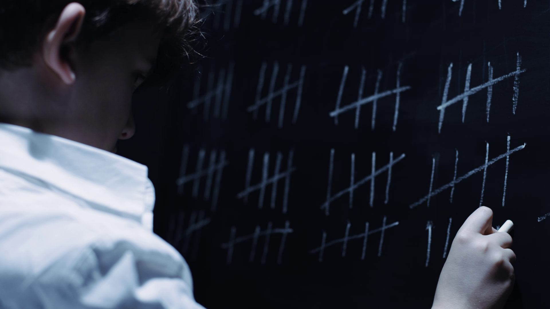 Photo of a kid drawing in a blackboard